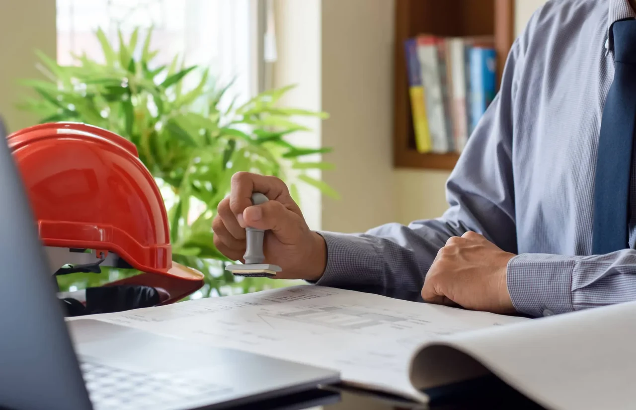 Validation administrative d’un projet immobilier logistique avec plans techniques et tampon officiel