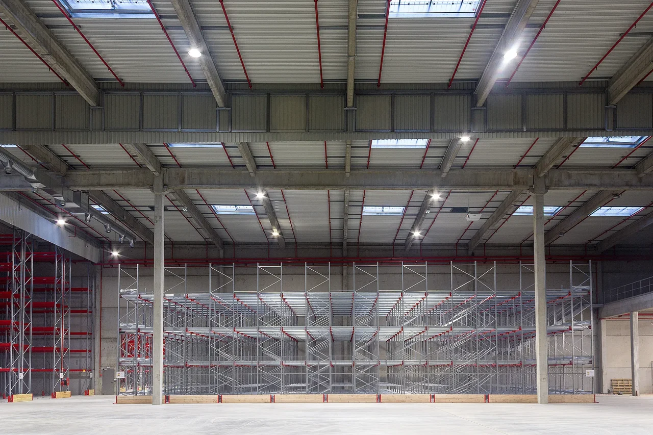 Intérieur entrepôt logistique Muret avec racks stockage grande hauteur et charpente béton