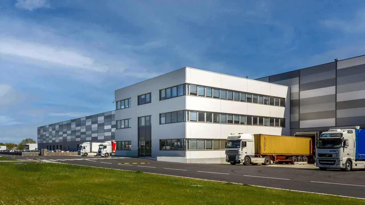 Plateforme logistique Muret Toulouse avec camions en quais et bâtiment bureaux en façade
