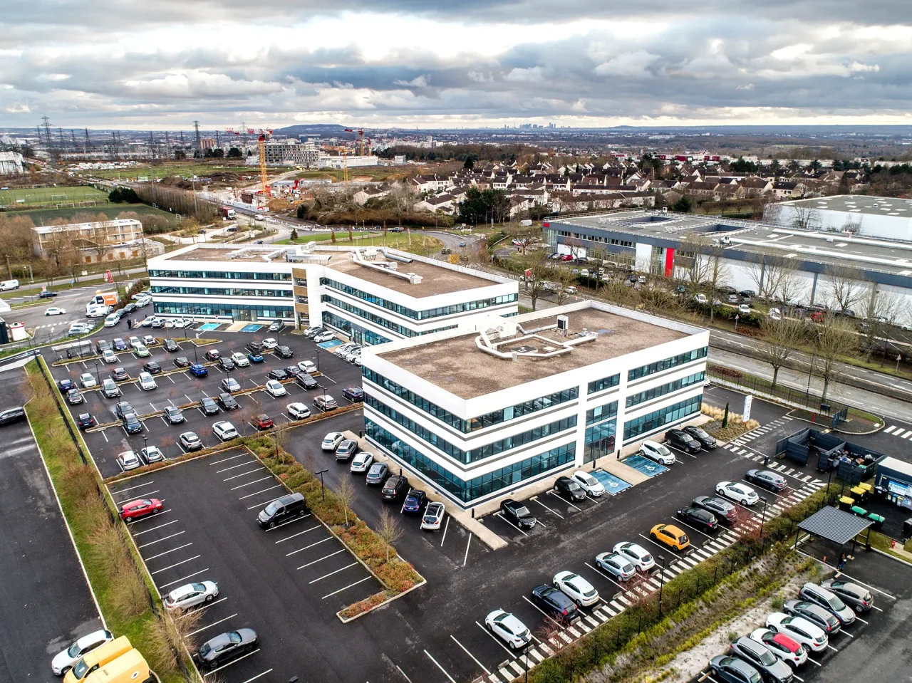 Vue aérienne de deux immeubles tertiaires Vectura Park à Cergy avec parkings et environnement économique