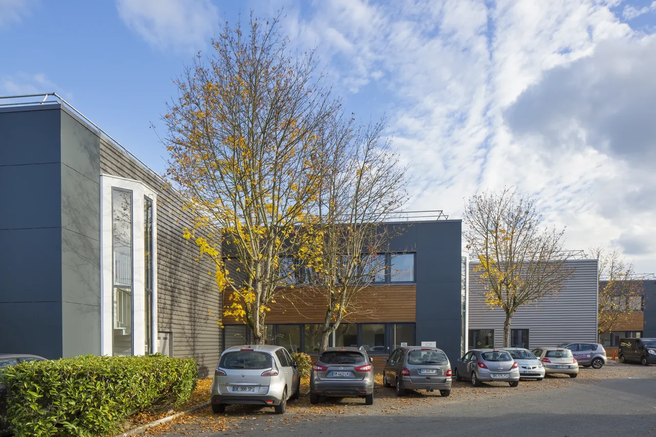 Bâtiments d’activités rénovés avec parking et arbres au Vectura Park Sainte-Geneviève-des-Bois