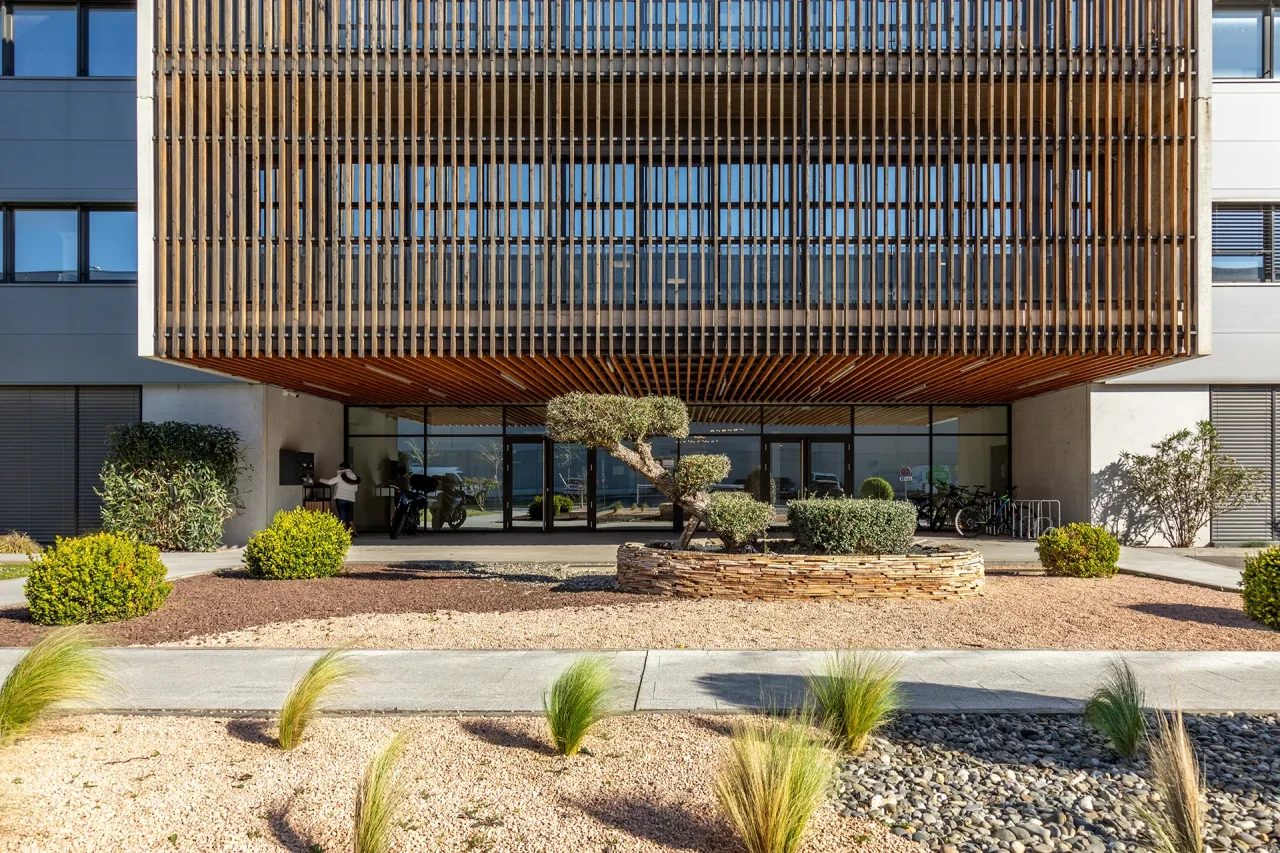 Entrée d’un bâtiment d’activités ACTISUD à Toulouse avec façade bois et aménagement paysager