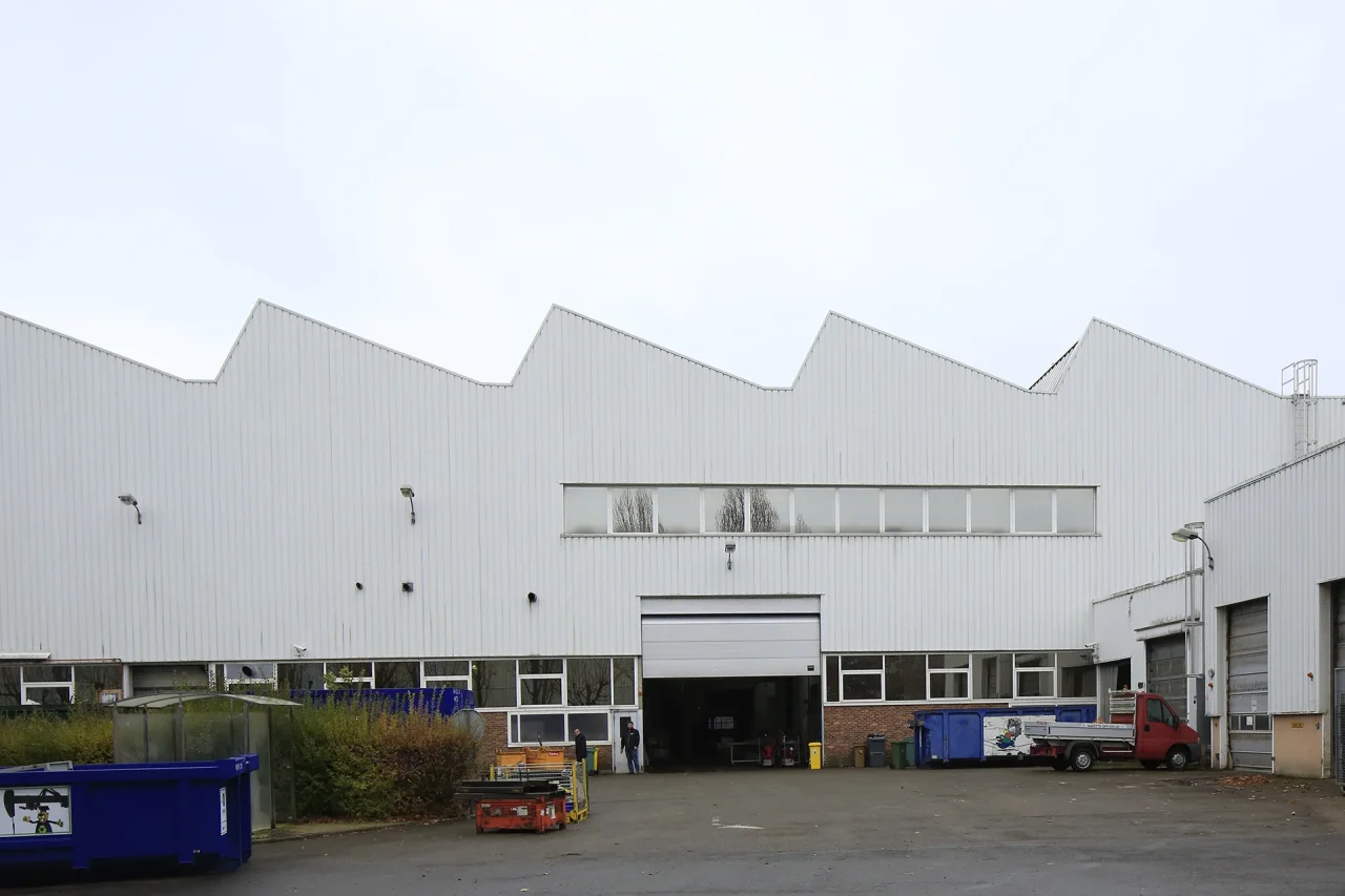 entrepôt industriel avant réhabilitation avec façade métallique et accès logistique existant