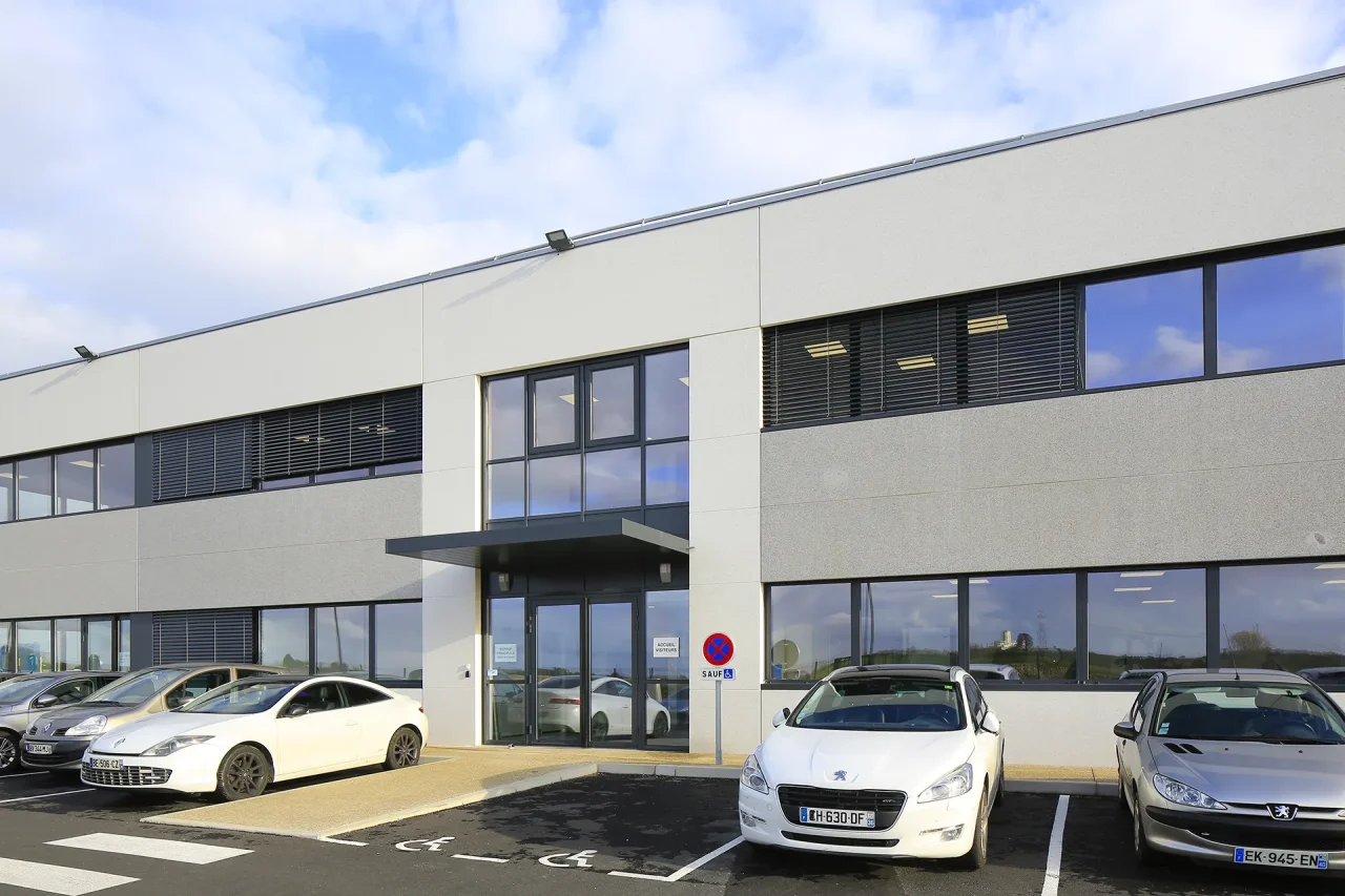 Entrée bureaux unité de production Lisi Aerospace Châteauroux avec parking et façade vitrée