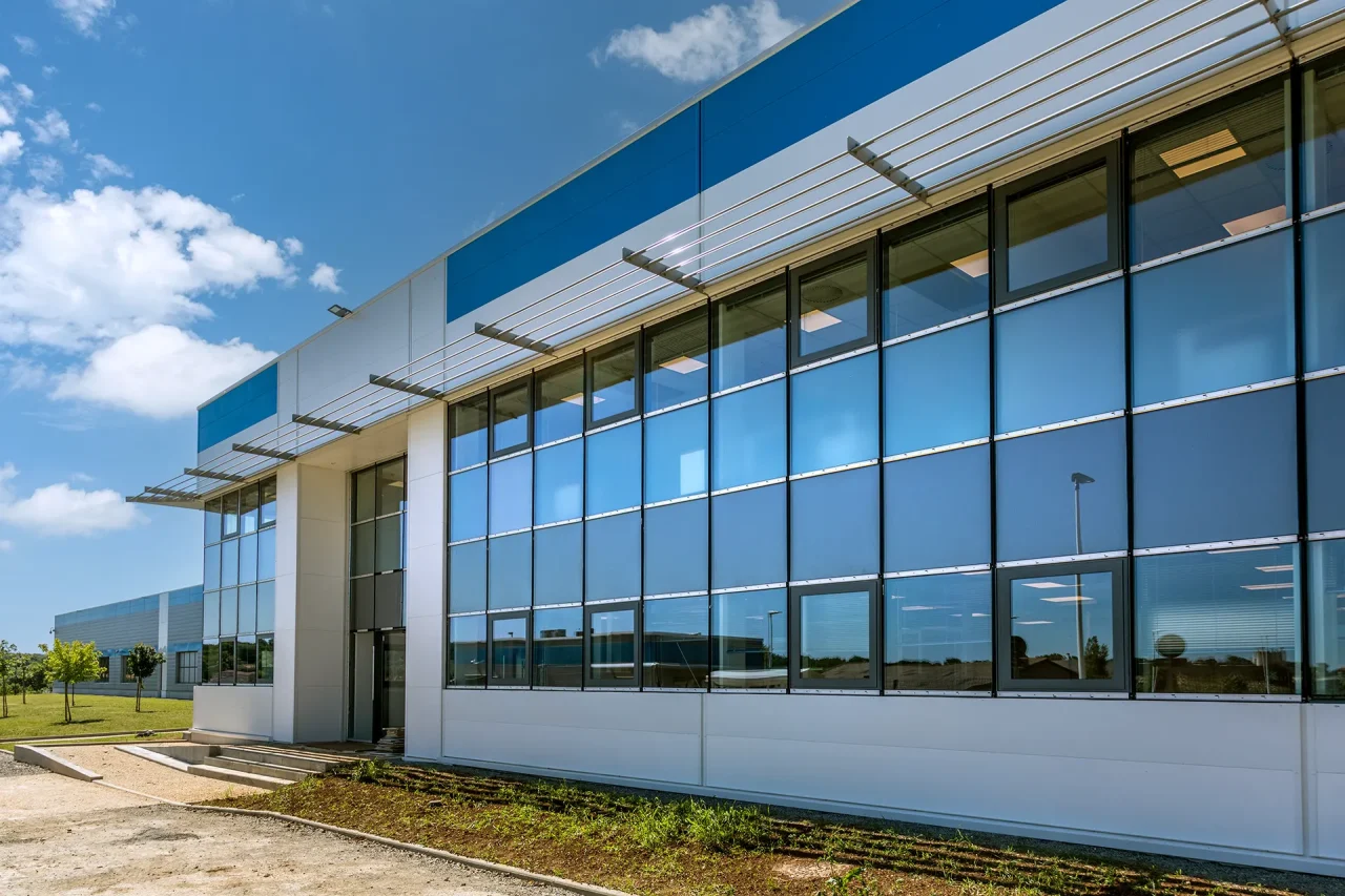 Façade de bureaux avec grandes surfaces vitrées et brise-soleil sur site industriel à Villefranche-de-Rouergue