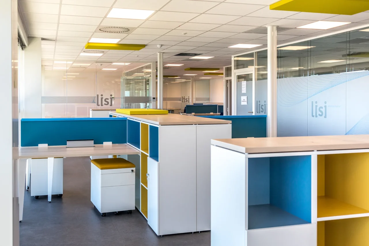 Open space aménagé avec postes de travail et rangements colorés dans bâtiment industriel à Villefranche-de-Rouergue