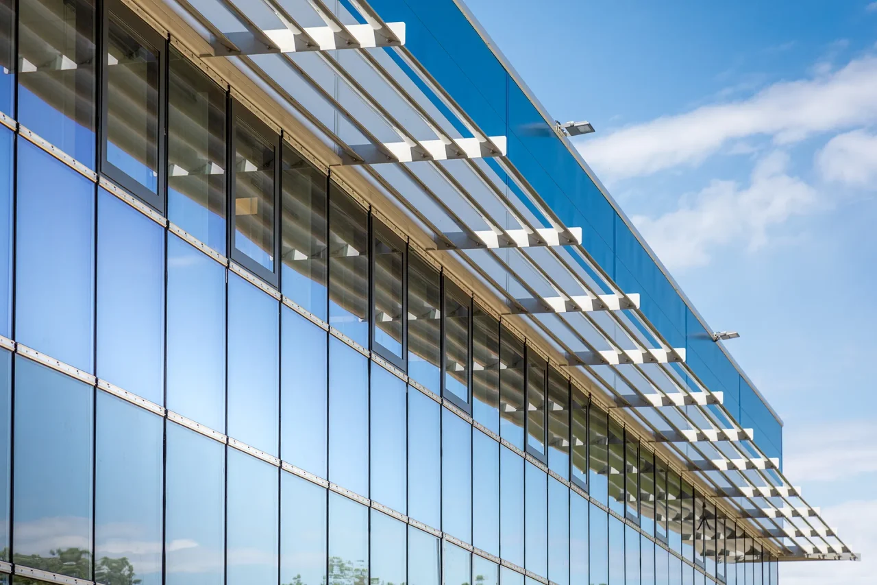 Façade en verre avec brise-soleil métalliques sur bâtiment industriel à Villefranche-de-Rouergue