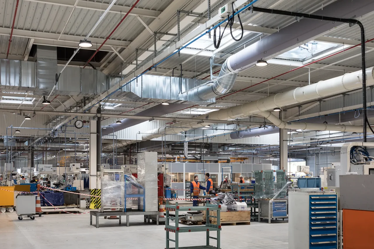Atelier industriel avec machines de production et réseaux de ventilation en toiture pour activité aéronautique