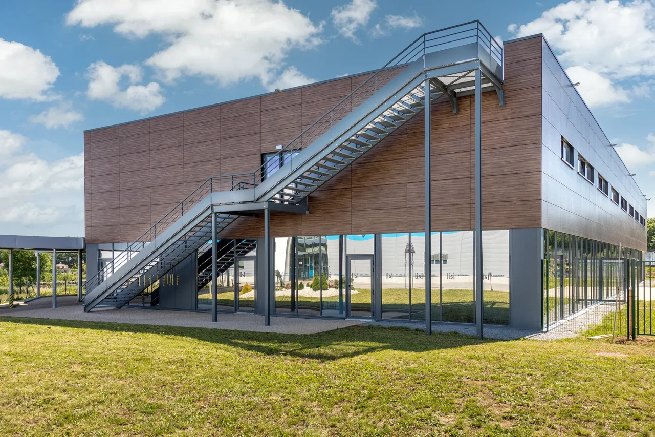 Façade locaux sociaux avec escalier extérieur métallique et bardage bois sur site LISI Aerospace