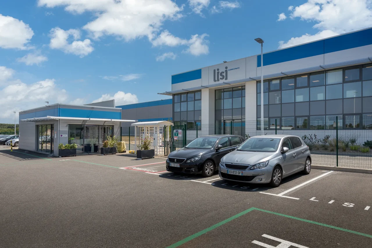 Entrée du site industriel LISI Aerospace à Villefranche-de-Rouergue avec bâtiment de production et parking